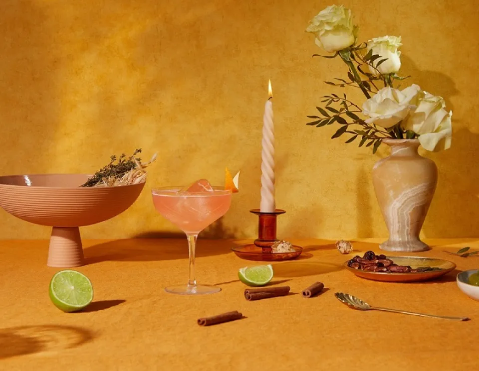 Cointreau's The Thanksipping cocktail for Thanksgiving in front of a lit candle, limes, and cinnamon