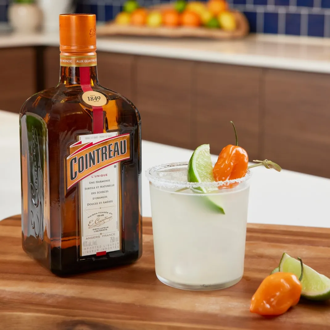 A Smoky Margarita in a rocks glass next to a Cointreau bottle