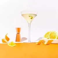 The Cointreau Daiquiri cocktail surrounded by orange peels, oranges, and a shaker