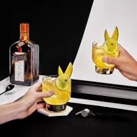 The Mango Madness cocktail in a rocks glass next to a bottle of Cointreau