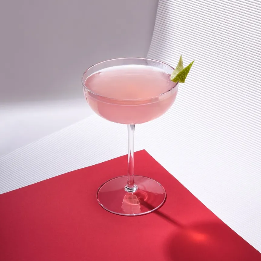 The Alt' Cosmopolitan in a wine glass, garnished with a lime peel